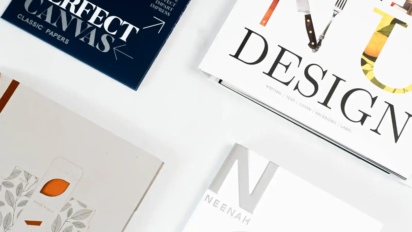 Design books and printed brochure samples arranged on a white surface