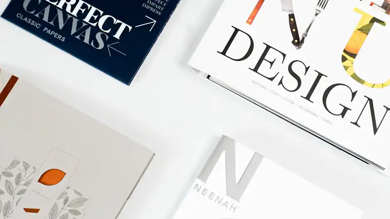 Design books and printed brochure samples arranged on a white surface