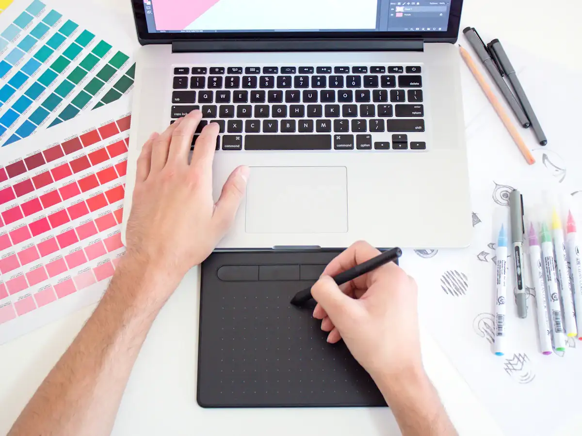 Designer using a drawing tablet and laptop with colour swatches