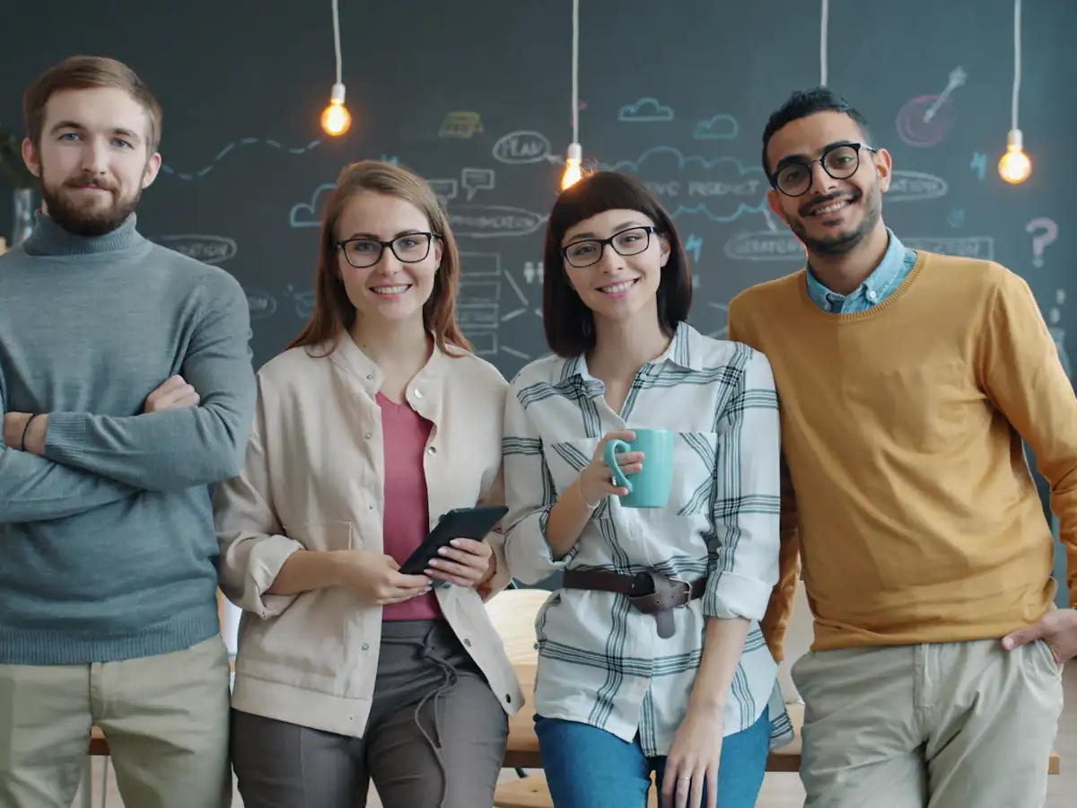 Four smiling colleagues standing together in a modern office