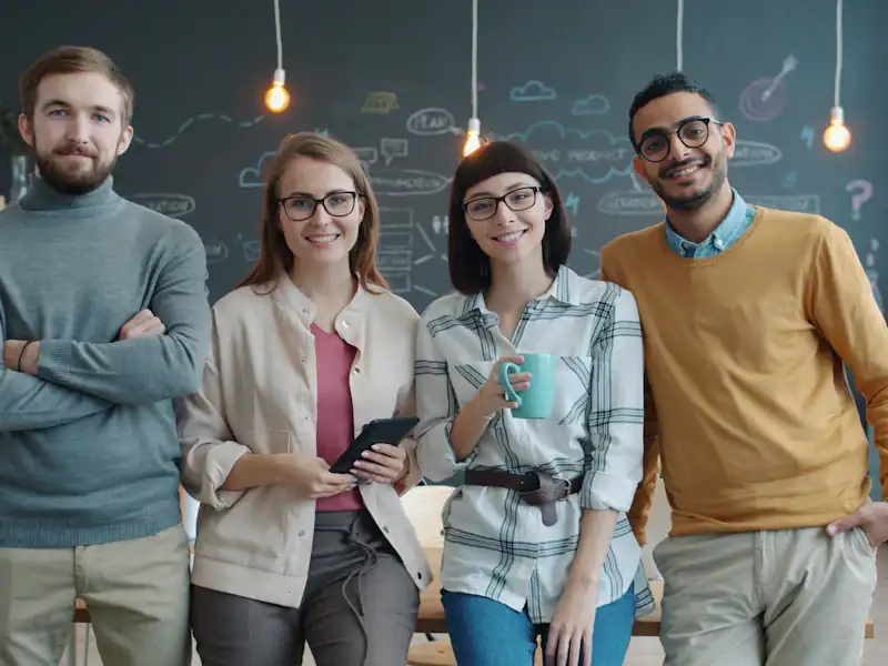 Four smiling colleagues standing together in a modern office