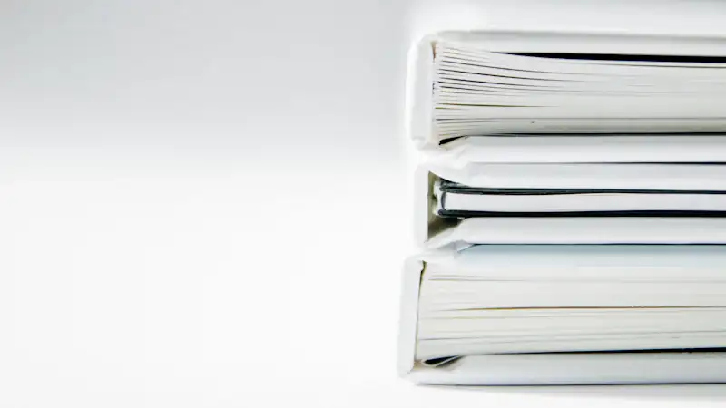 A stack of thick document folders on a white surface