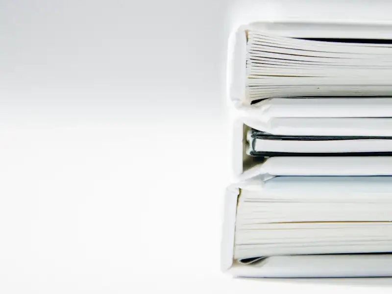 A stack of thick document folders on a white surface