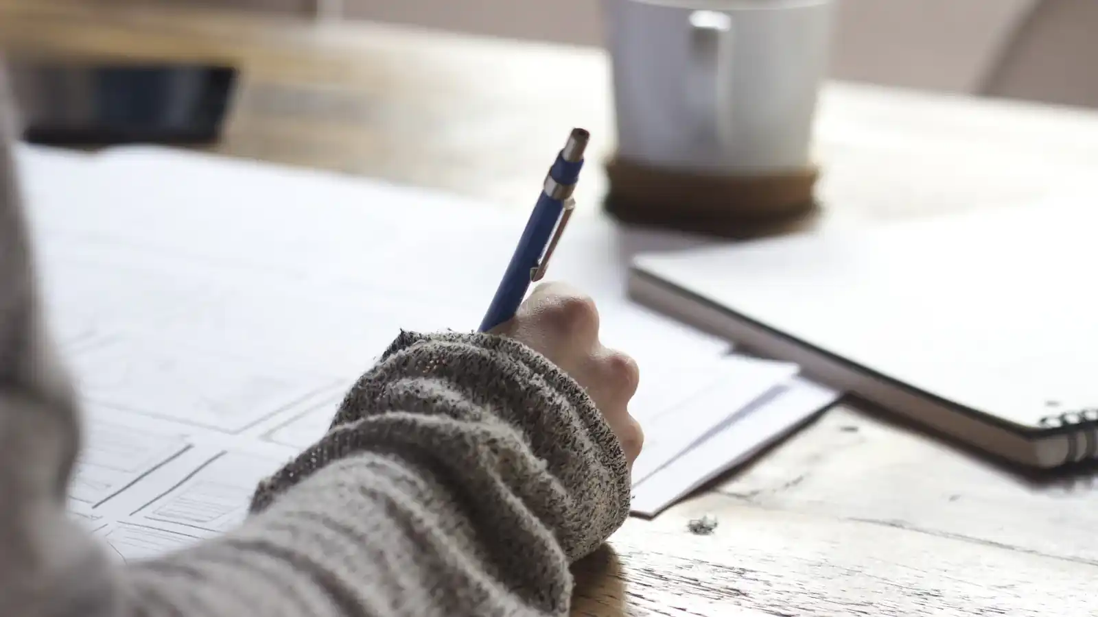 Writing notes in a notebook next to a laptop