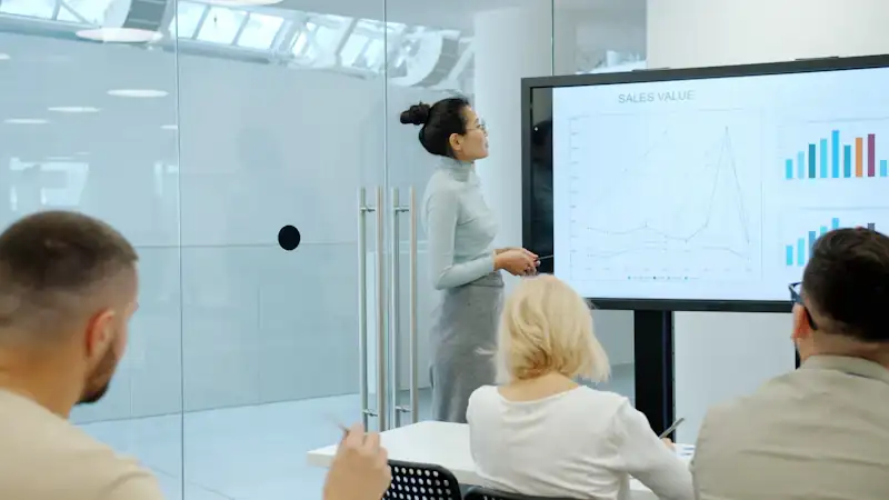 Woman presenting charts on a screen to colleagues