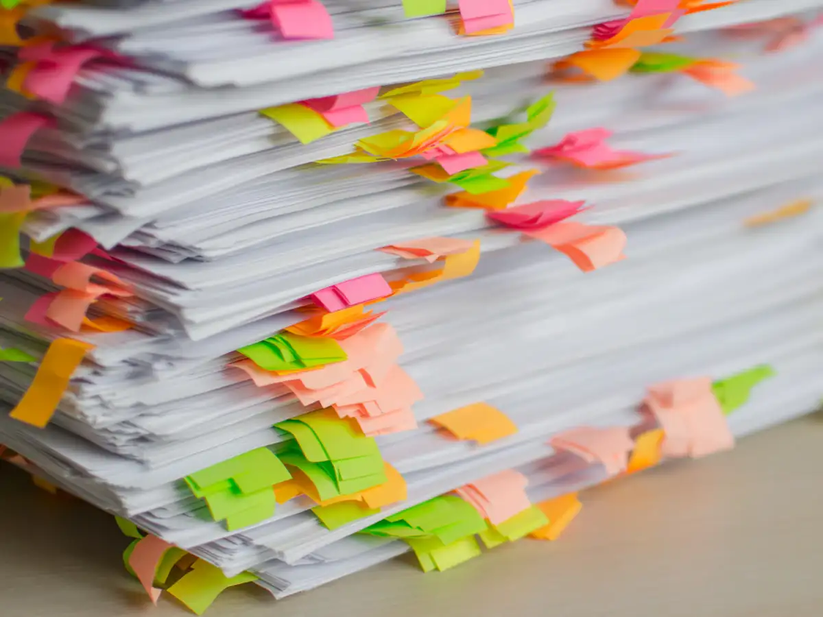 Stack of papers marked with colourful sticky tabs for review